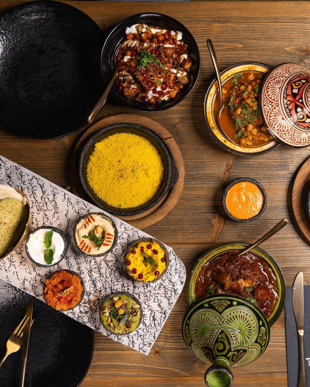 A table of Moroccan dishes seen from above: couscous, tagines, dips and salads