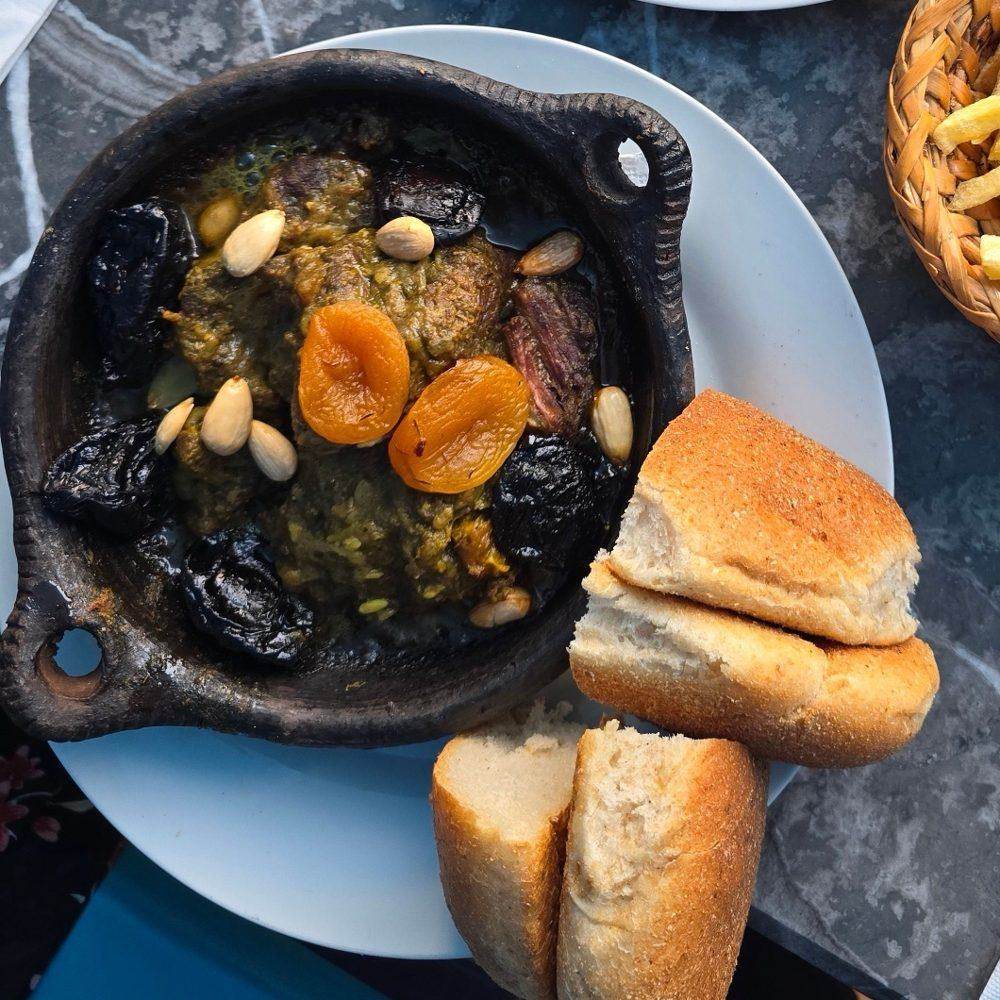 A Moroccan tagine of meat with prunes, apricots and almonds, served with fresh bread