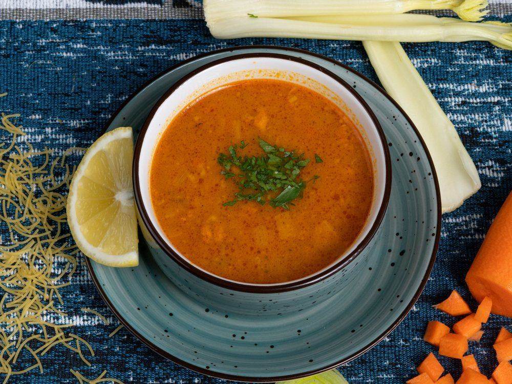 A bowl of Moroccan harira soup with parsley and a lemon wedge